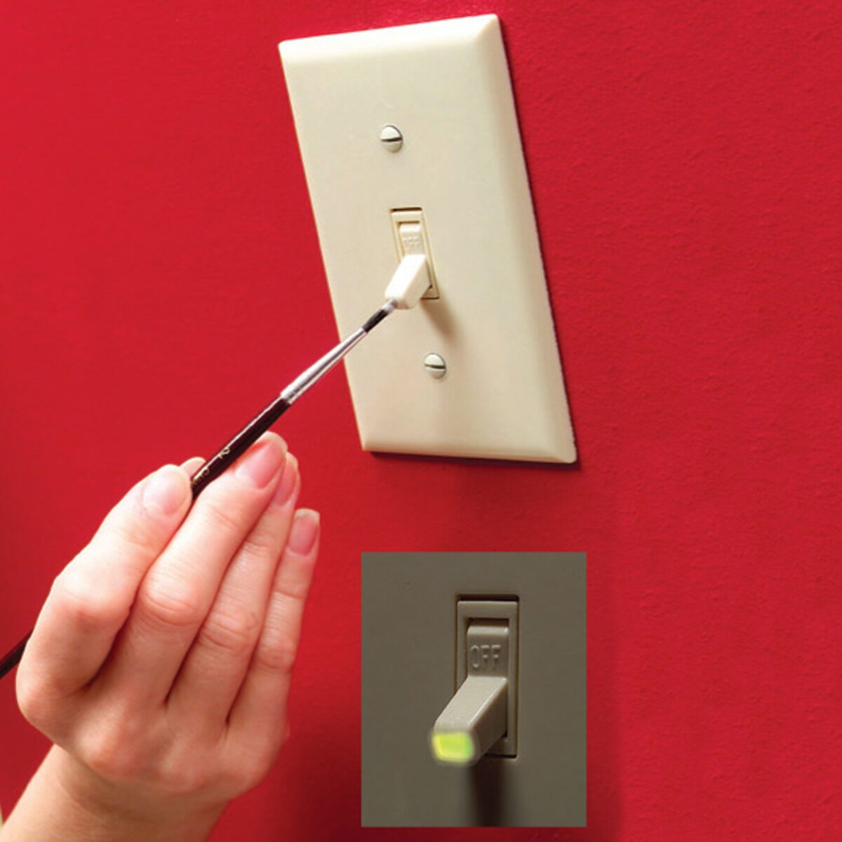 A hand is using a brush to flick a light switch on a red wall, indicating an action to turn the light on or off.