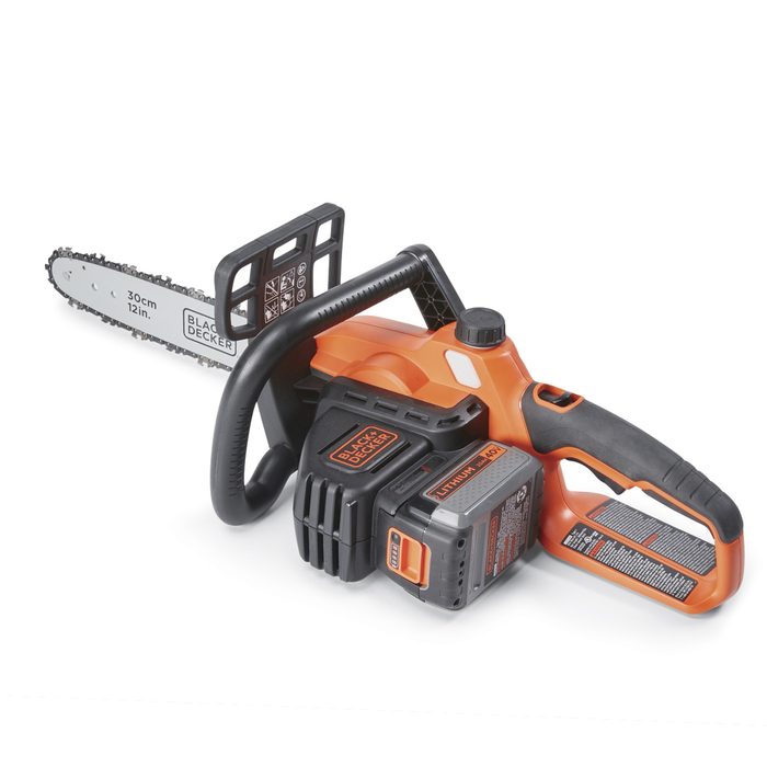 A chainsaw rests on a flat surface, featuring a black and orange design, with a blade extending from its front, ready for use in cutting.