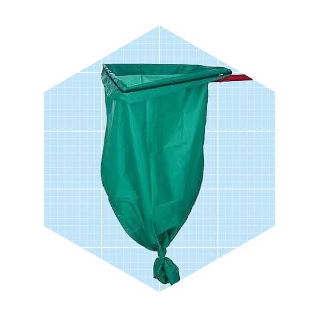 A green trash bag hangs from a support, containing waste, in a simple, grid-patterned background.
