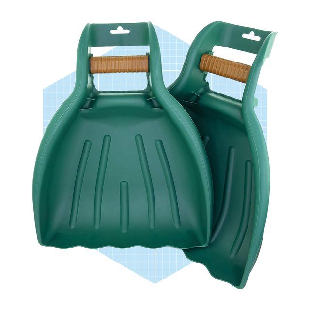 Two green plastic dustpans rest against each other, featuring textured handles, set against a light blue geometric background.
