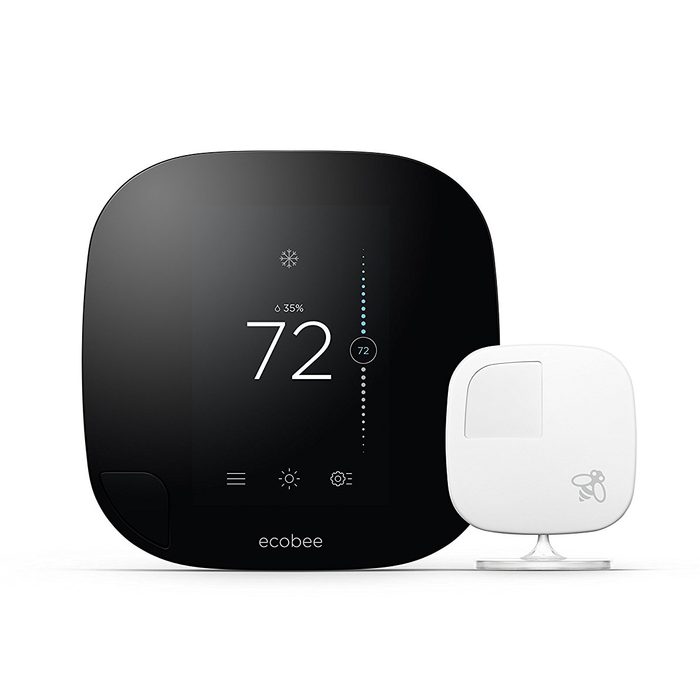 A smart thermostat displays a temperature of 72°F, showing humidity levels. It sits beside a small sensor, designed for home climate control.