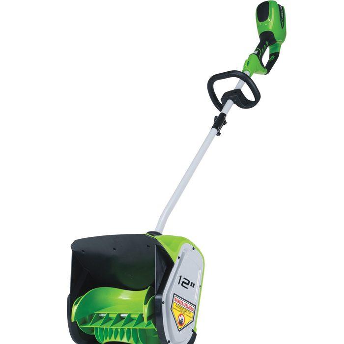 A battery-operated snow shovel, green and black, rests upright with a 12-inch wide scoop, designed for clearing snow from driveways or sidewalks.