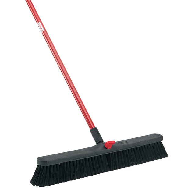 A red-handled broom with a wide black bristle head stands upright, ready for use in sweeping floors or surfaces clean.