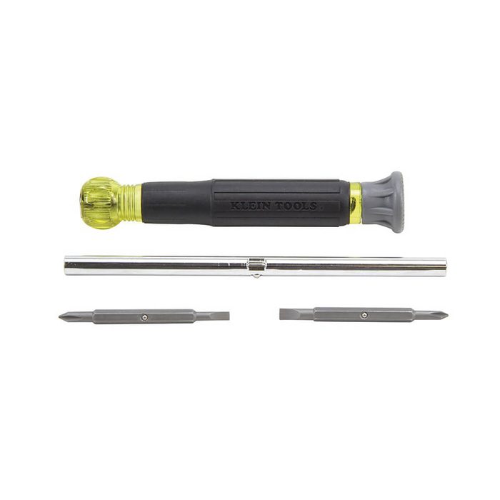 A screwdriver with interchangeable bits lies on a flat surface, featuring a yellow and black handle alongside two metal bits and a metal extension.