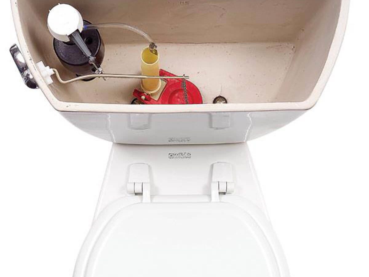 A toilet tank, open and showing internal components like a float, chain, and valve, is positioned above a white toilet bowl in a bathroom setting.