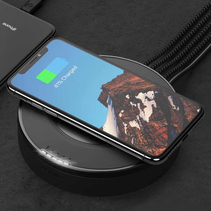 A smartphone is charging wirelessly on a sleek black pad, displaying a 41% battery status against a scenic mountain background on its screen.
