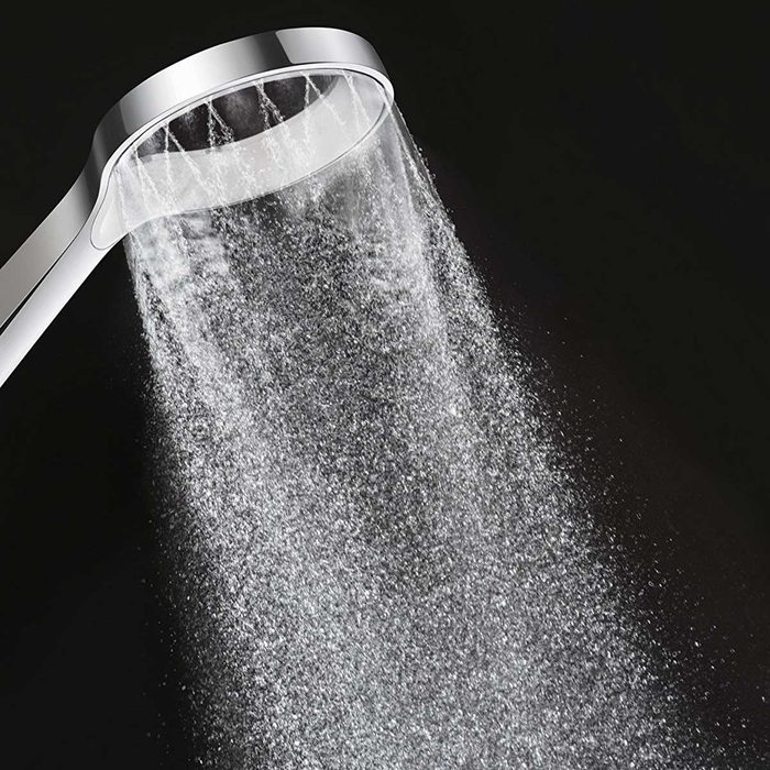 A showerhead releases a fine spray of water, creating a cascading flow against a dark background, suggesting a refreshing bathing experience.