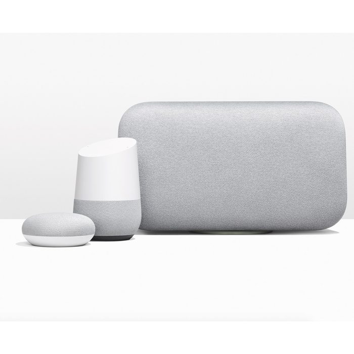 Three smart speakers are displayed on a white surface, with two larger devices in gray fabric, and a smaller white and gray speaker beside them.