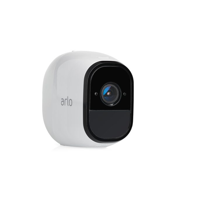 A small, white security camera displays a circular lens. It is designed for monitoring, likely placed outdoors or in a home setting.