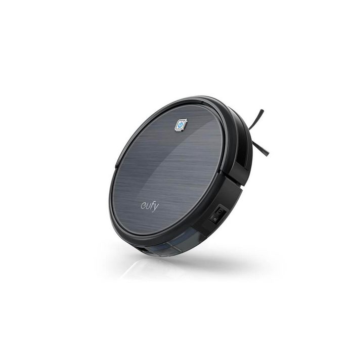 A round robotic vacuum cleaner moves, designed to autonomously collect dirt and debris from floors in a home environment.