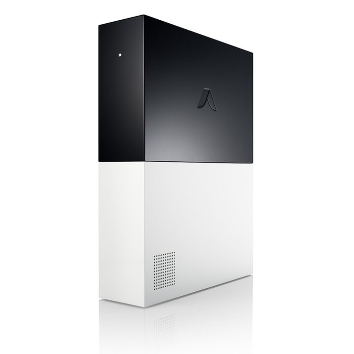 A sleek, modern device stands vertically, with a black upper section and a white lower section, reflecting a minimalist design in a bright, uncluttered space.