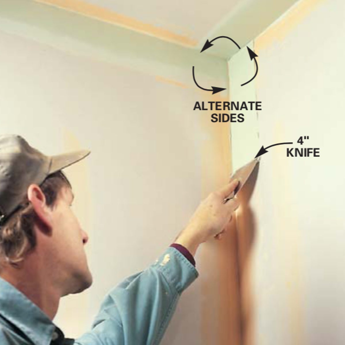 A person applies joint compound with a knife in a corner, demonstrating alternating sides technique while working in a room with light-colored walls.