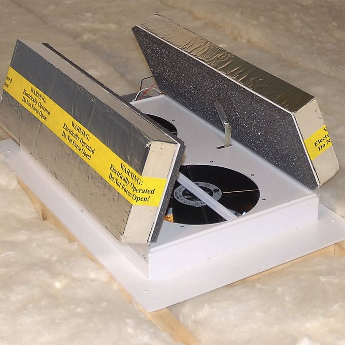 A machine with two hinged panels displays spinning records. It is situated on a soft, insulated surface, featuring caution labels about its electrical operation.