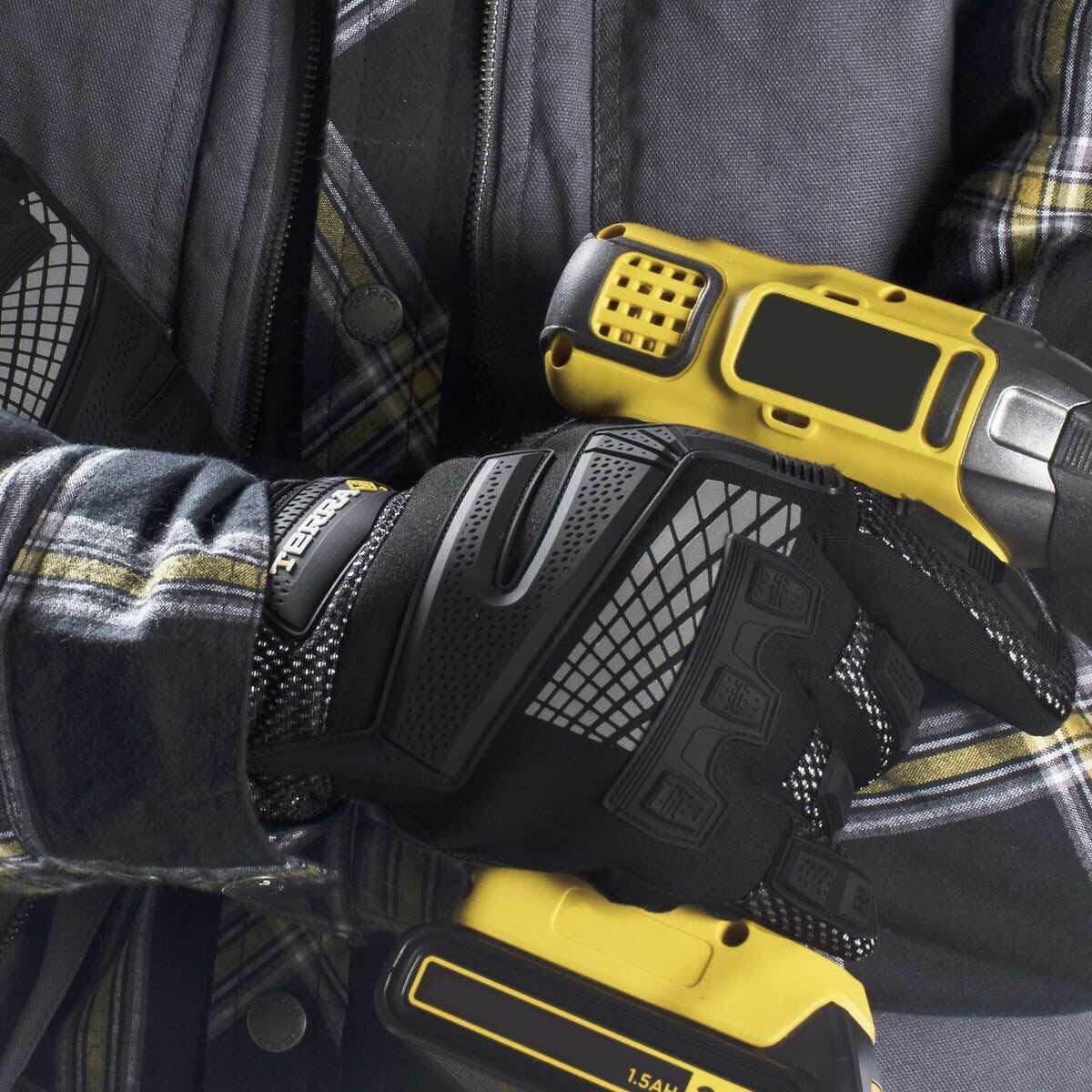 A gloved hand holds a yellow and black tool, while the wearer is dressed in a plaid shirt and a dark jacket.