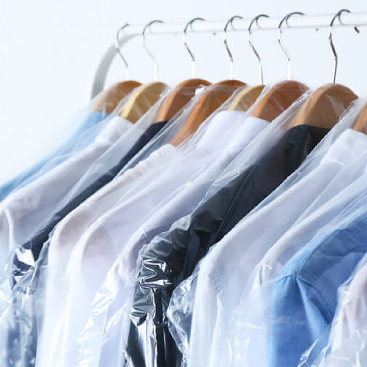 Shirts hung on hangers in clear plastic covers, awaiting use, arranged neatly against a light backdrop.