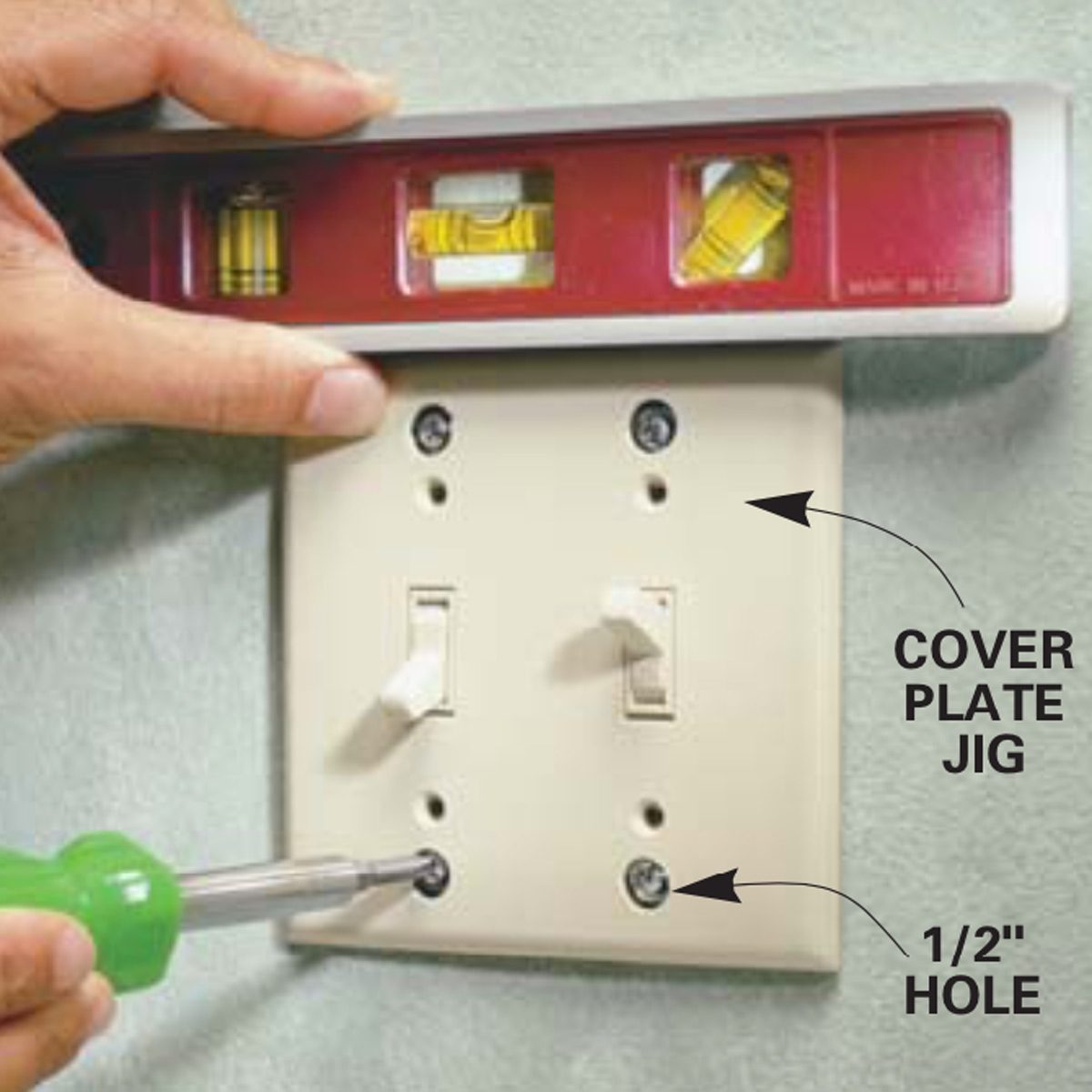 A hand holds a level above a wall plate, while another hand uses a screwdriver to secure it, indicating installation in a home setting.