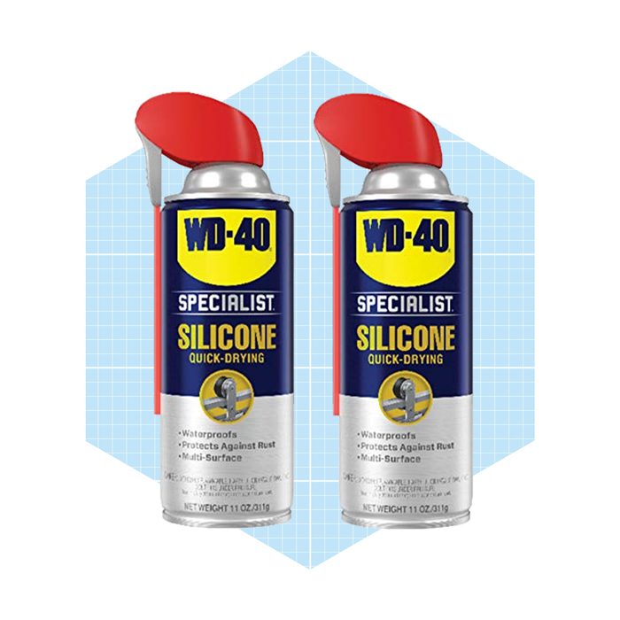 Two spray cans of WD-40 Specialist Silicone Quick-Drying are displayed against a light blue, grid-patterned background, emphasizing their labeling and intended function.