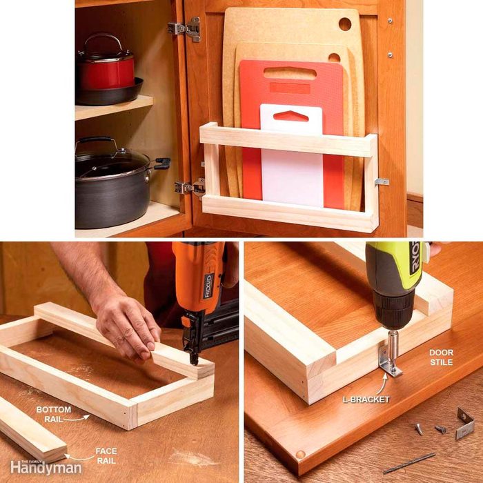 A person assembles a wooden frame inside a kitchen cabinet to hold cutting boards, while tools and parts are arranged on a work surface nearby.