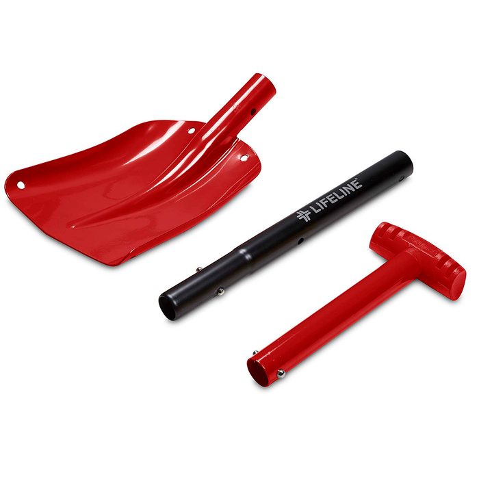 A red shovel, black handle, and red hammer lie together, suggesting tools for digging or moving material, typically used in outdoor or construction contexts.