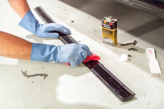 someone cleaning old adhesive from the back side of the car's body side molding