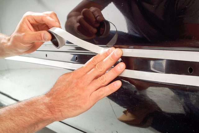 someone applying the double-stick molding tape on car door