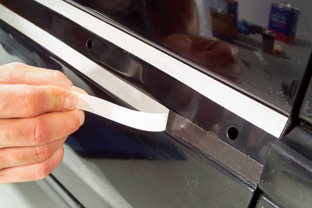 someone peeling the protective film off the tape to expose the sticky surface