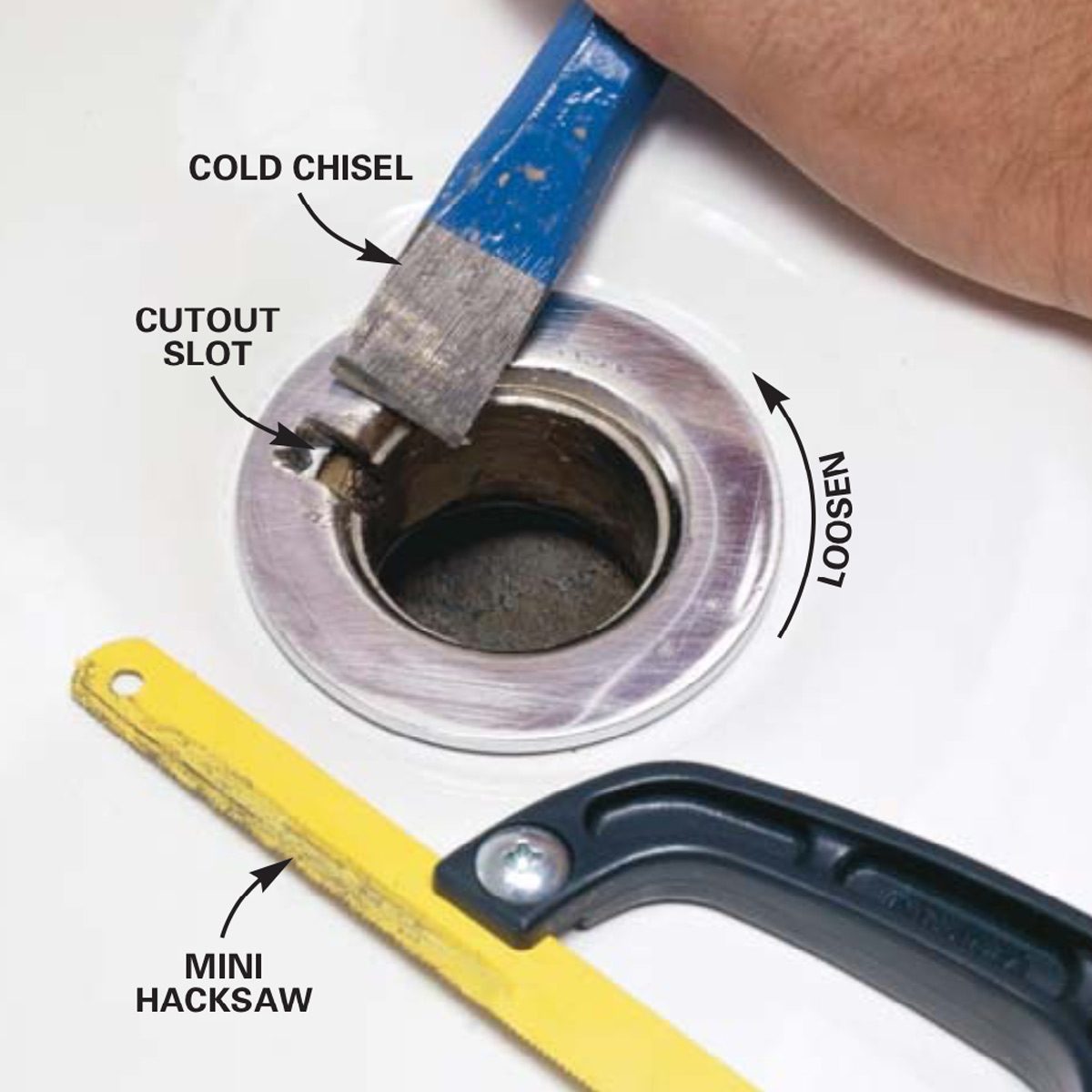 A blue cold chisel is positioned over a cutout slot, while a mini hacksaw rests nearby, indicating a plumbing or repair task on a surface.