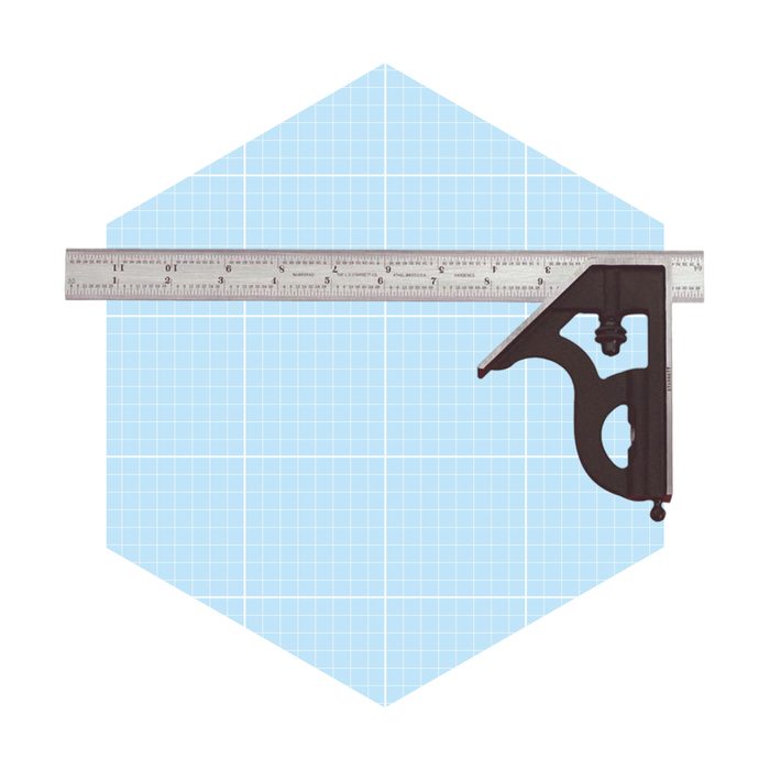 A metal square ruler and black framing square are positioned over a light blue grid background, indicating a design or drafting task in progress.
