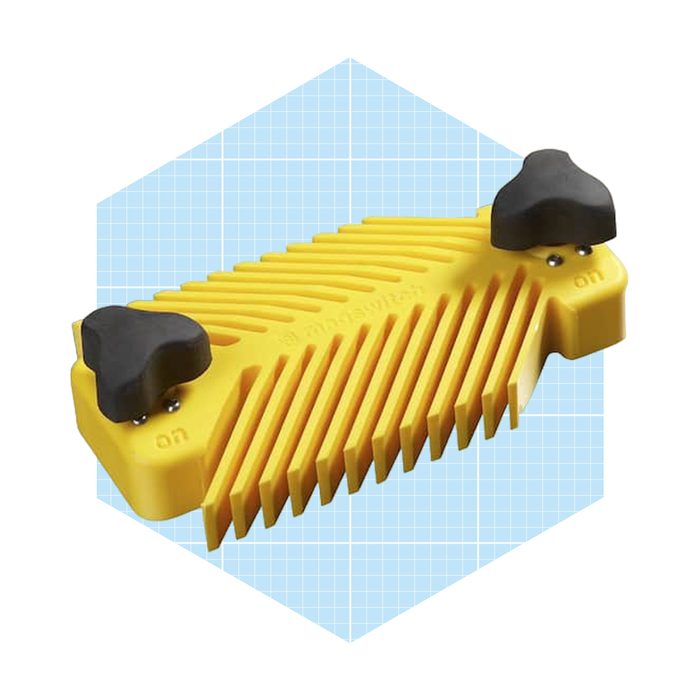 A yellow, ribbed object with black toggle switches is positioned on a light blue grid background, suggesting a functional tool or device.