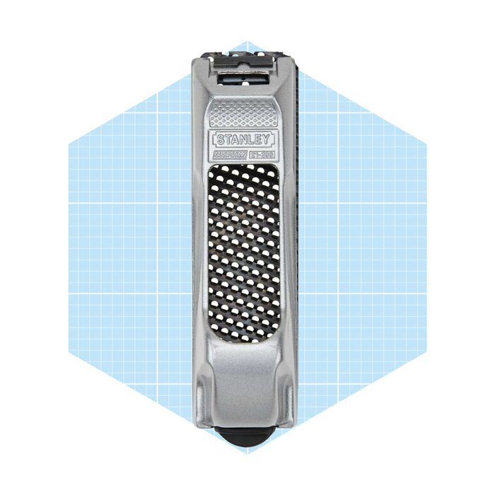 A silver utility knife is positioned vertically, showcasing its handle and blade compartment against a light blue grid background.