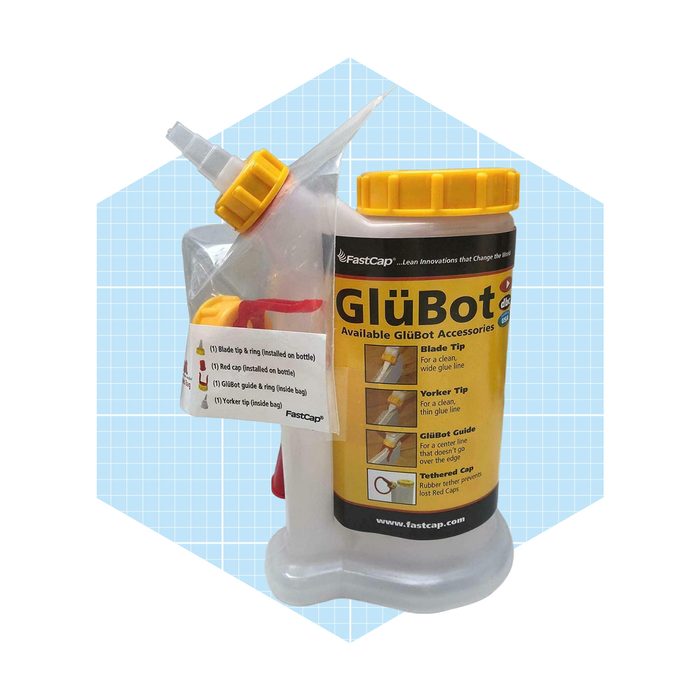 A glue bottle with multiple tips and accessories is positioned against a patterned blue background, ready for use in crafting or construction projects.