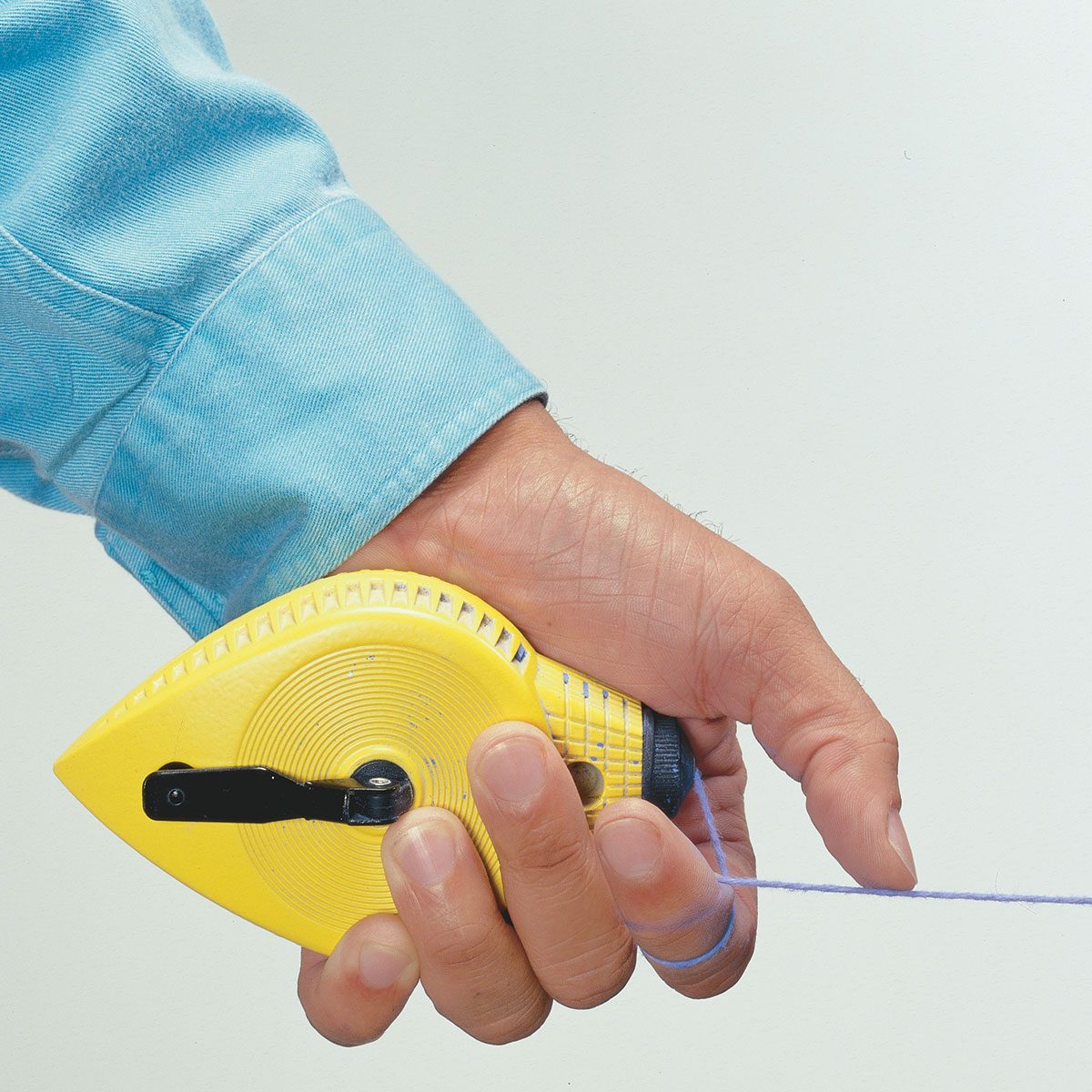 Hand holding a chalkline with a thumb on the string | Construction Pro Tips