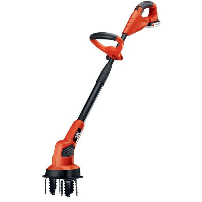 A gardening tool, with a long handle and three sharp tines, is designed for breaking up soil and aerating gardens. It is brightly colored orange and black.