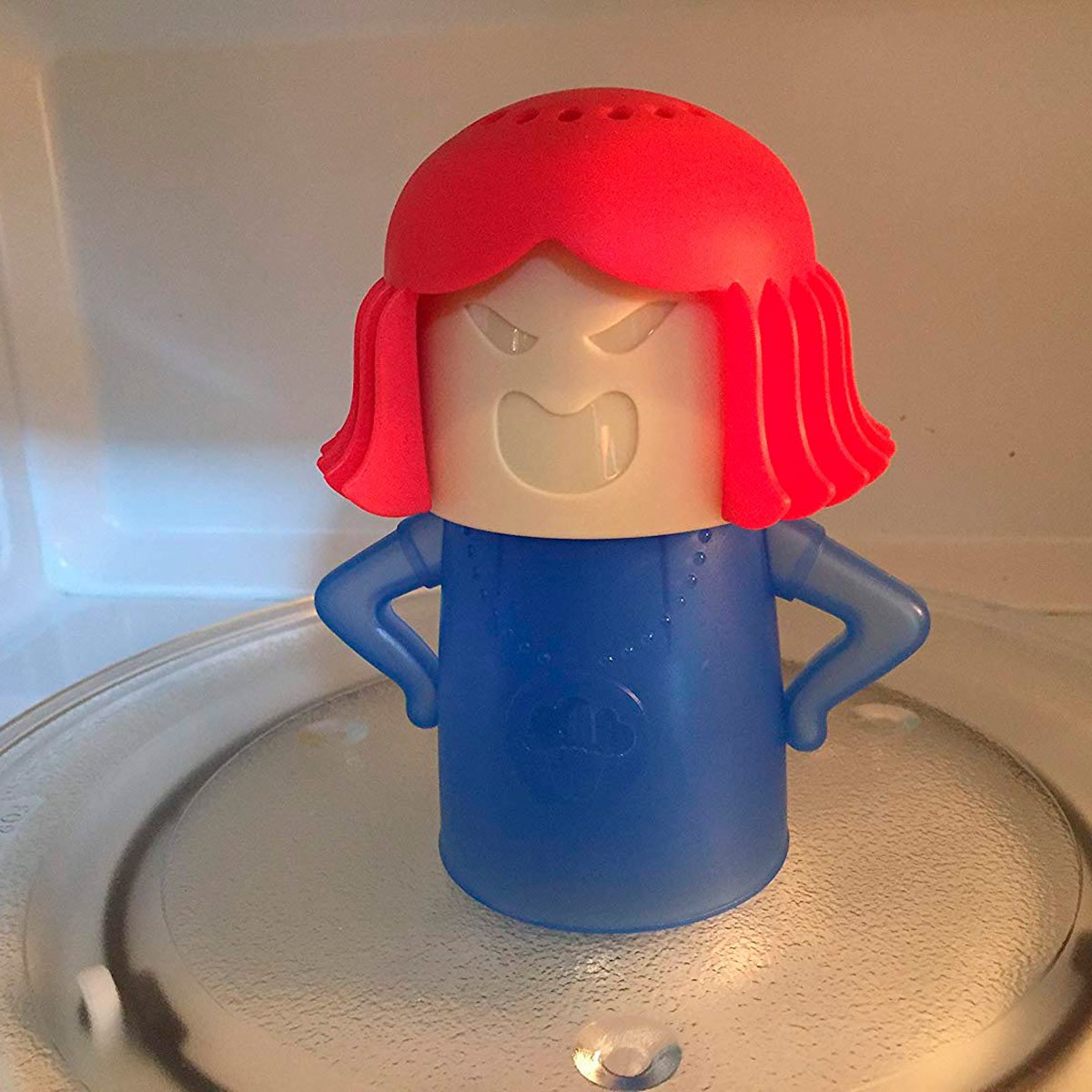 A cartoonish, blue-and-red character stands with hands on hips inside a microwave, appearing to frown with a fierce expression as it heats up.