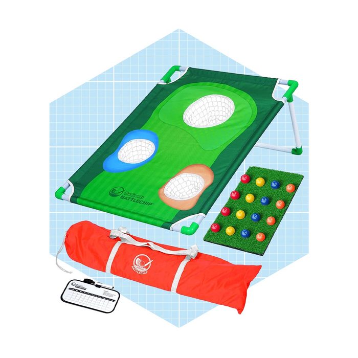 A green game mat with target holes sits alongside a colorful scoring board and a red carrying bag, all placed on a light blue grid background.