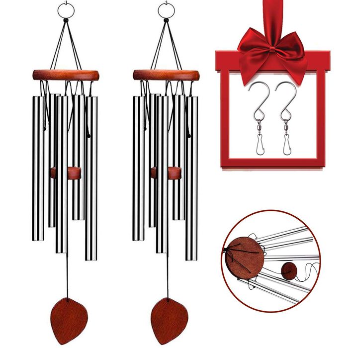 Two wind chimes hang suspended, producing sound. A gift box nearby features hooks. The setting appears decorative, likely suited for outdoor or indoor ambiance.