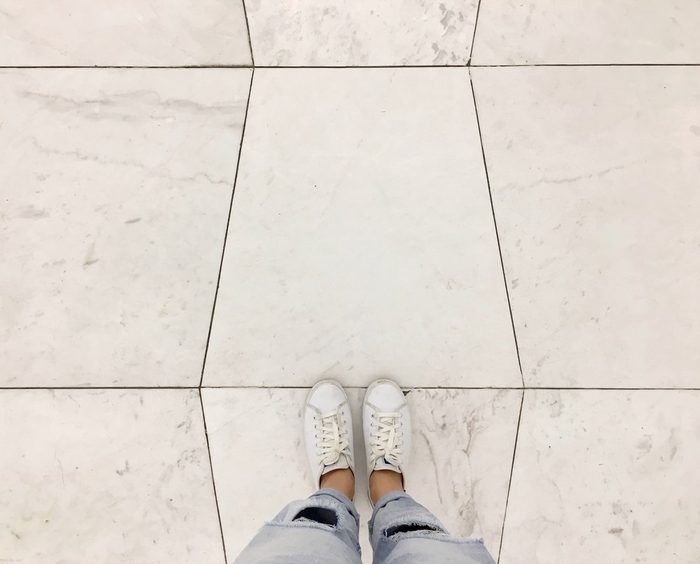 Top view selfie of sneakers shoes on white tiles floor background with copy space