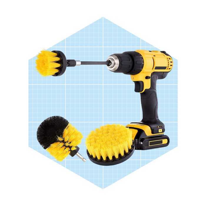 A cordless drill stands with various yellow-bristled scrub brush attachments beside it, set against a light blue grid background.