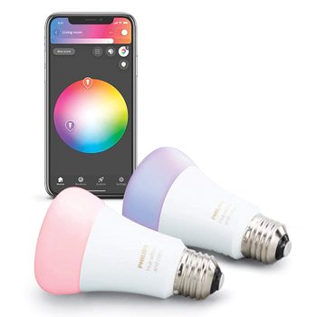 Two smart light bulbs rest on a surface while a smartphone displays a color selection app, showcasing a color wheel for setting light hues.