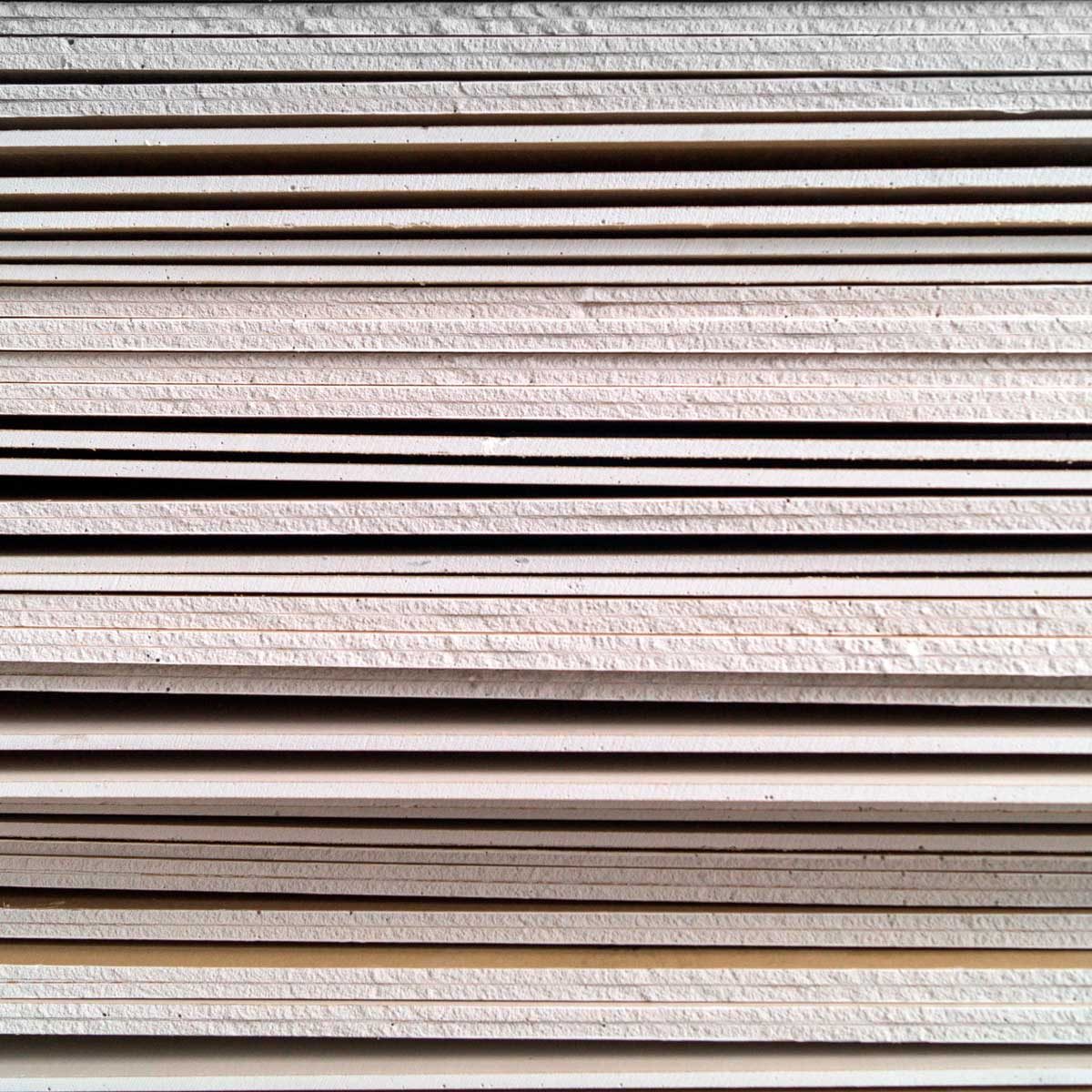 Stacks of textured, off-white paper lie neatly arranged, showcasing layers and uniform edges against a simple, unobtrusive background.