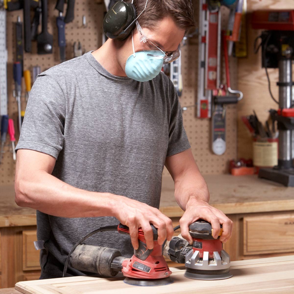 Man-holding-two-random-orbit-sanders