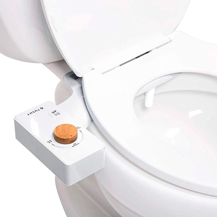 A modern toilet features a control panel on the side, equipped with a wooden dial for adjusting functions, positioned in a clean bathroom setting.