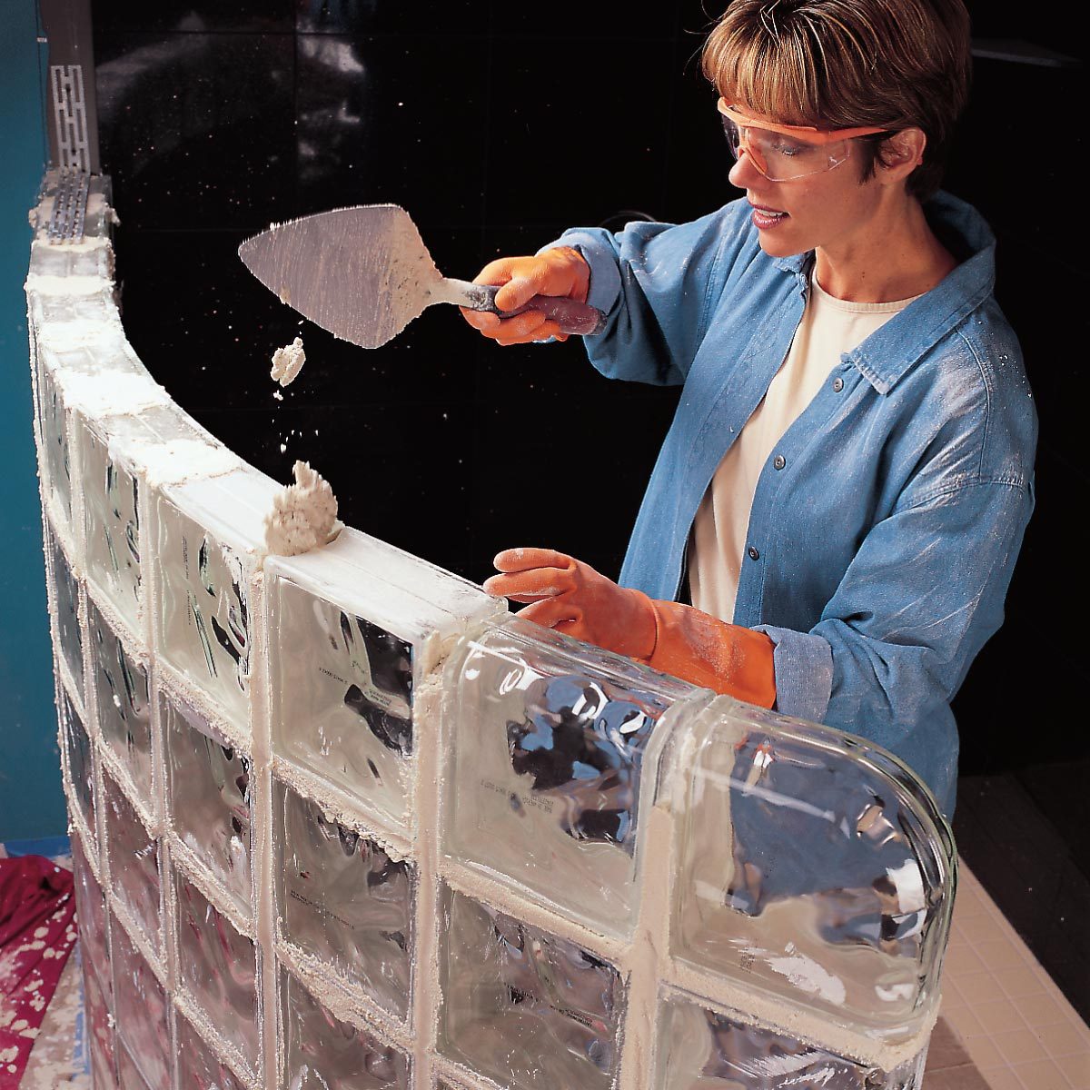 filling the joints with mortar to install a glass block shower