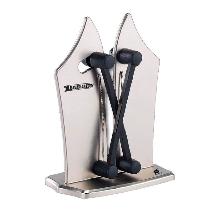 A knife sharpener stands upright, featuring two angled metal blades and adjustable black rods. It is designed for sharpening knives efficiently on a flat surface.