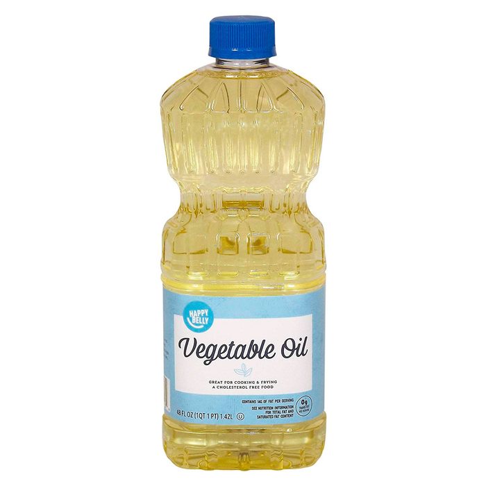 A clear plastic bottle of vegetable oil sits upright. It features a blue cap and a label indicating its uses, with a light yellow liquid inside.