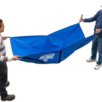 Two men hold a large blue fabric mat, stretching it between them. They are outdoors, preparing for use, possibly for a camping or outdoor activity.