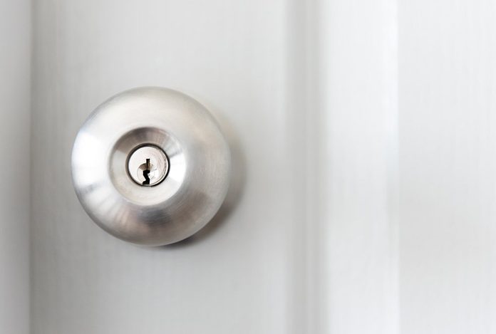 white door with metal doorknob is regular lock style in a house, copy space.