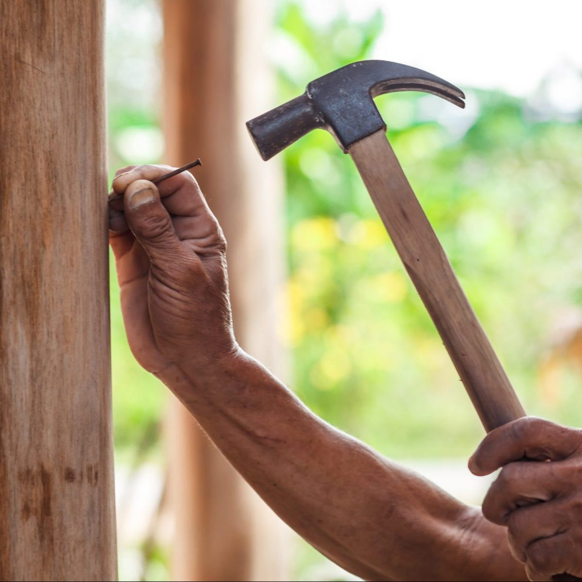 The carpenter is repairing the house. He makes nails using a hammer 