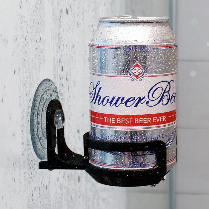 A can of beer is held by a suction-cup holder on a wet shower wall, with condensation visible on the can.