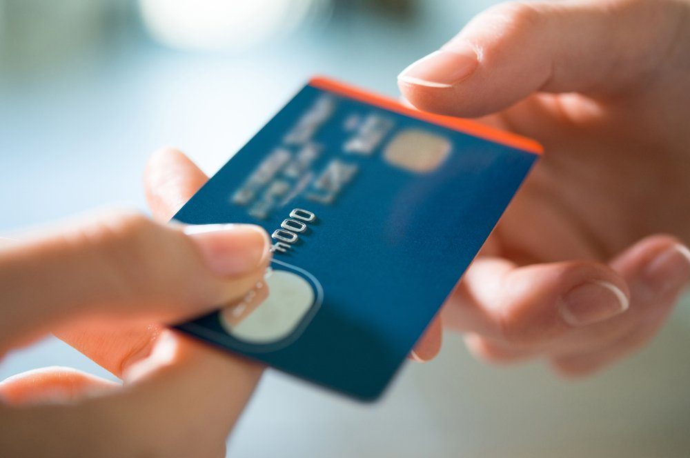 Closeup shot of a woman passing a payment credit card to the seller. Girl holding a credit card. Shallow depth of field with focus on the credit card.
